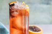 An Americano in a high ball glass with a blood orange garnish.