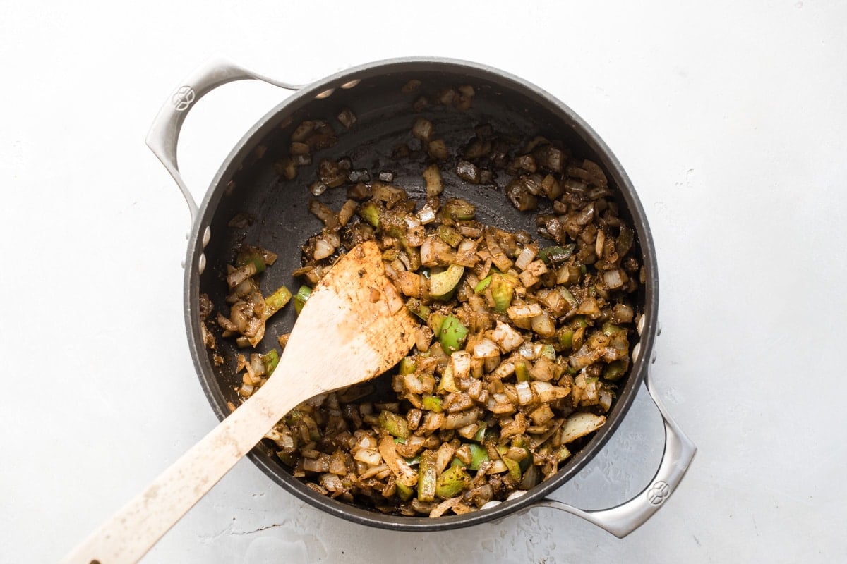 Chopped vegetables cooking in a black pot.