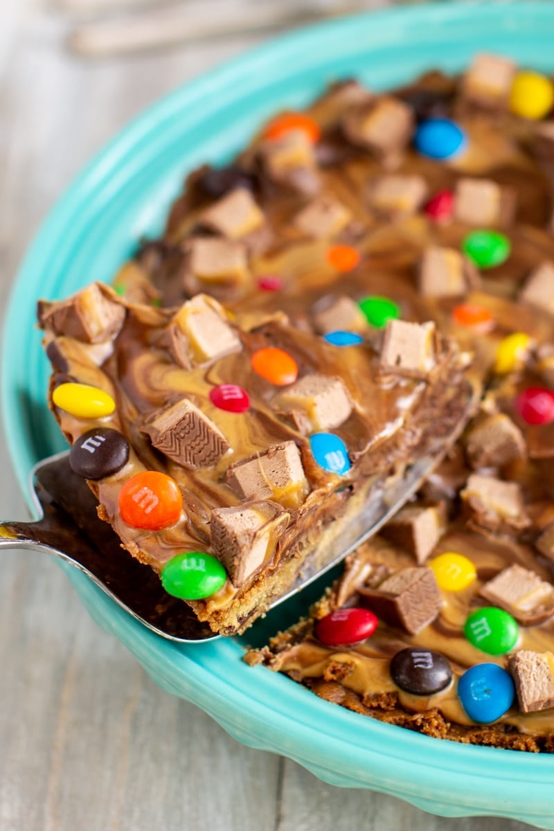 A chocolate chip cookie cake with a peanut butter swirl topping and chopped candy on top.