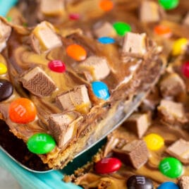 A chocolate chip cookie cake with a peanut butter swirl topping and chopped candy on top.