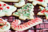 Frosted sugar cookies decorated for Christmas on a baking rack.