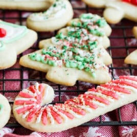 Frosted sugar cookies decorated for Christmas on a baking rack.