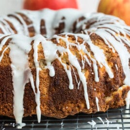 Cinnamon Apple Cake on a cooling rack surrounded by apples.