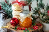 A jar of orange marmalade with a stack of biscuits, both wrapped as Christmas gift.