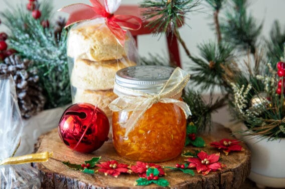 A jar of orange marmalade with a stack of biscuits, both wrapped as Christmas gift.