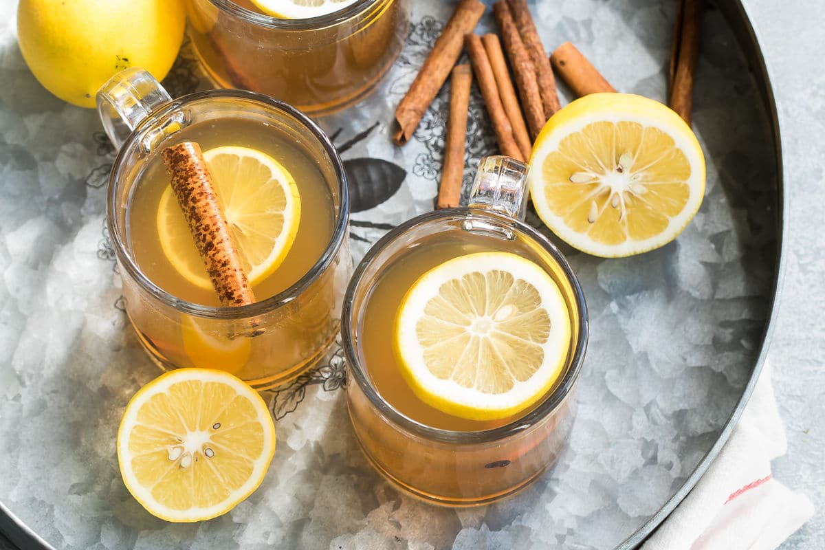 Hot toddy in clear mugs on a silver tray.