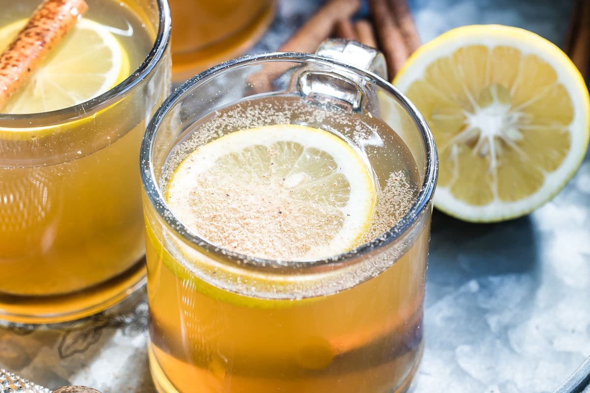 Hot toddy in clear mugs on a silver tray.
