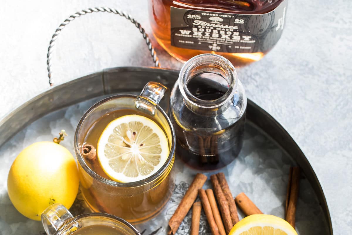 Hot toddy in clear mugs on a silver tray.
