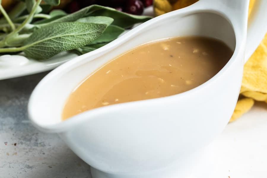 A white gravy boat filled with turkey gravy.