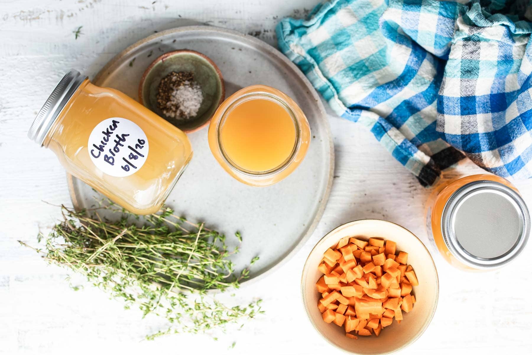 Homemade chicken broth in a jar on a plate.