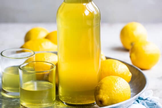 Limoncello in a bottle surrounded by lemons.
