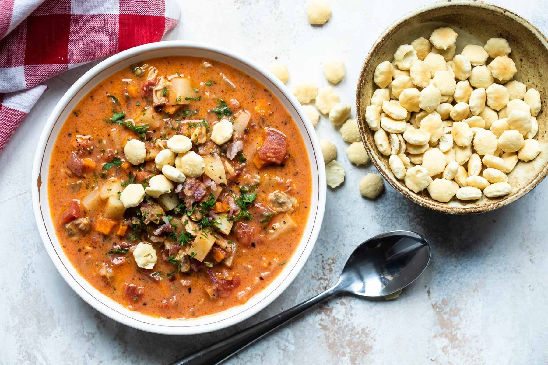 A bowl of Manhattan clam chowder soup with oyster crackers garnishing it.