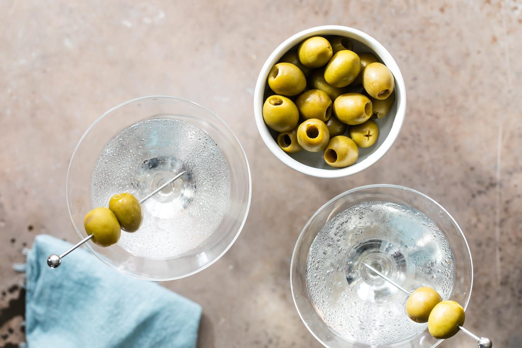Two dry martinis garnished with green olives.