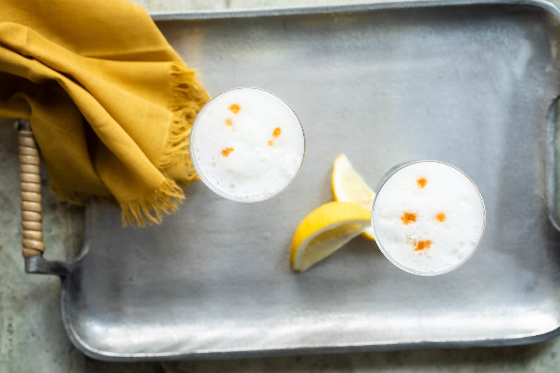 Two Pisco Sours in Nick and Nora glasses.