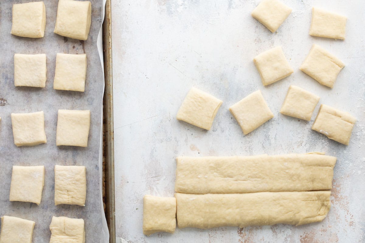 Beignet dough being sliced into squares.
