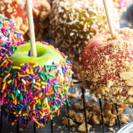 Decorated caramel apples on a cooling rack.