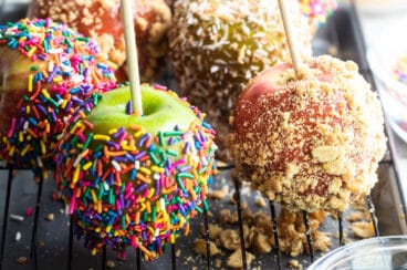 Decorated caramel apples on a cooling rack.