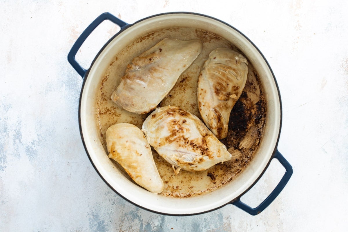 Chicken breasts being cooked in a Dutch oven.