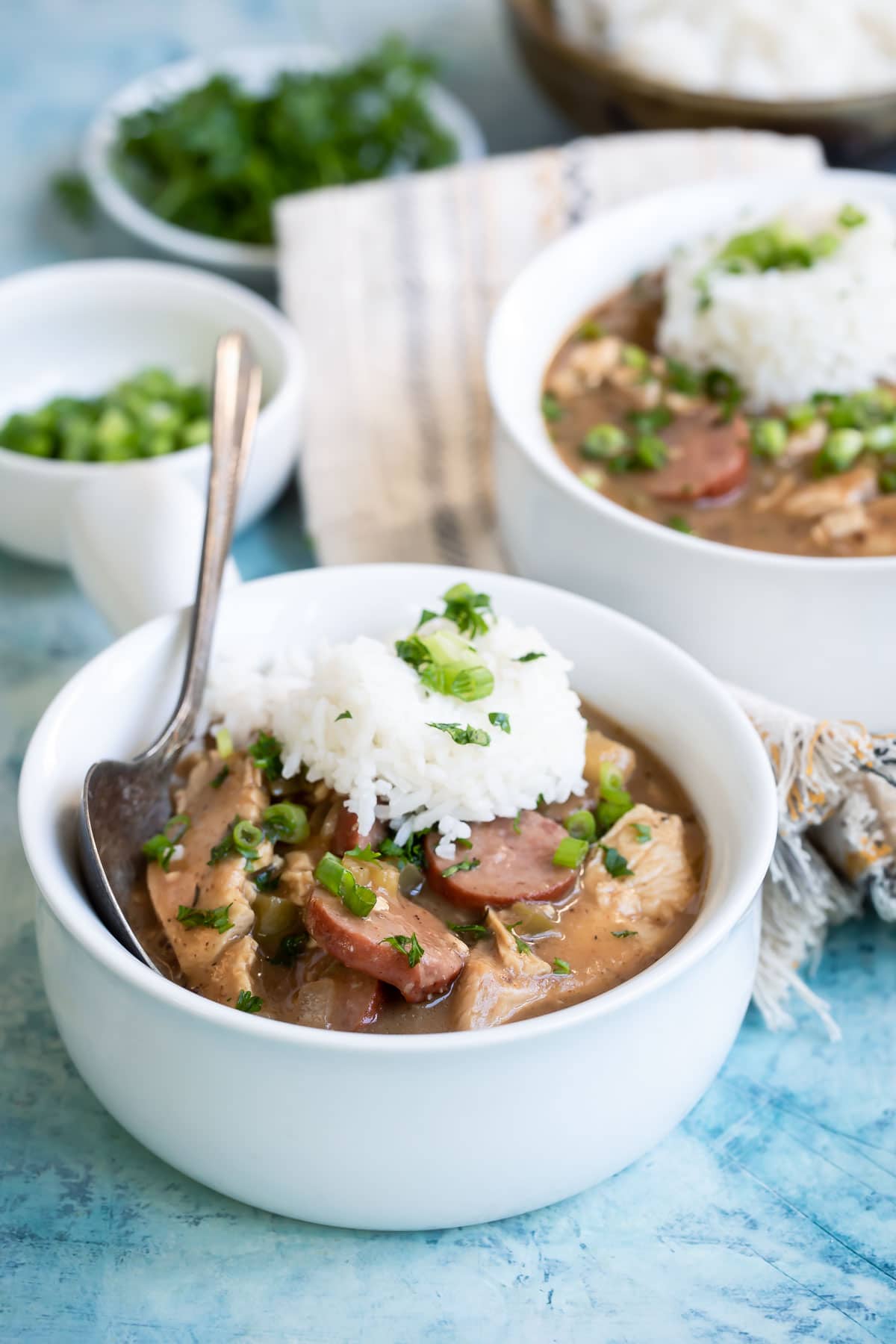 Chicken gumbo in a small white bowl with rice on top.