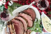 Prime rib cut into slices on a white platter with a serving fork.