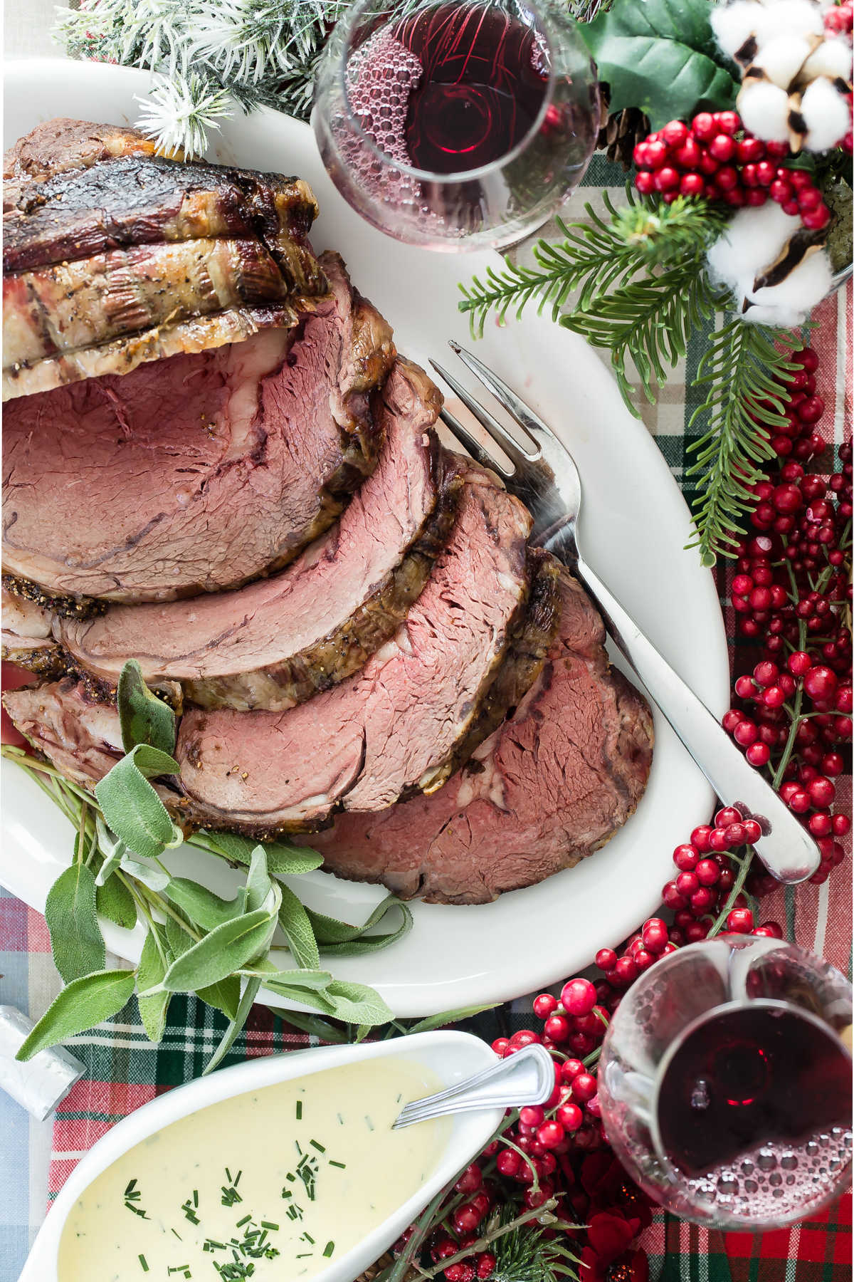 Prime rib cut into slices on a white platter with a serving fork.