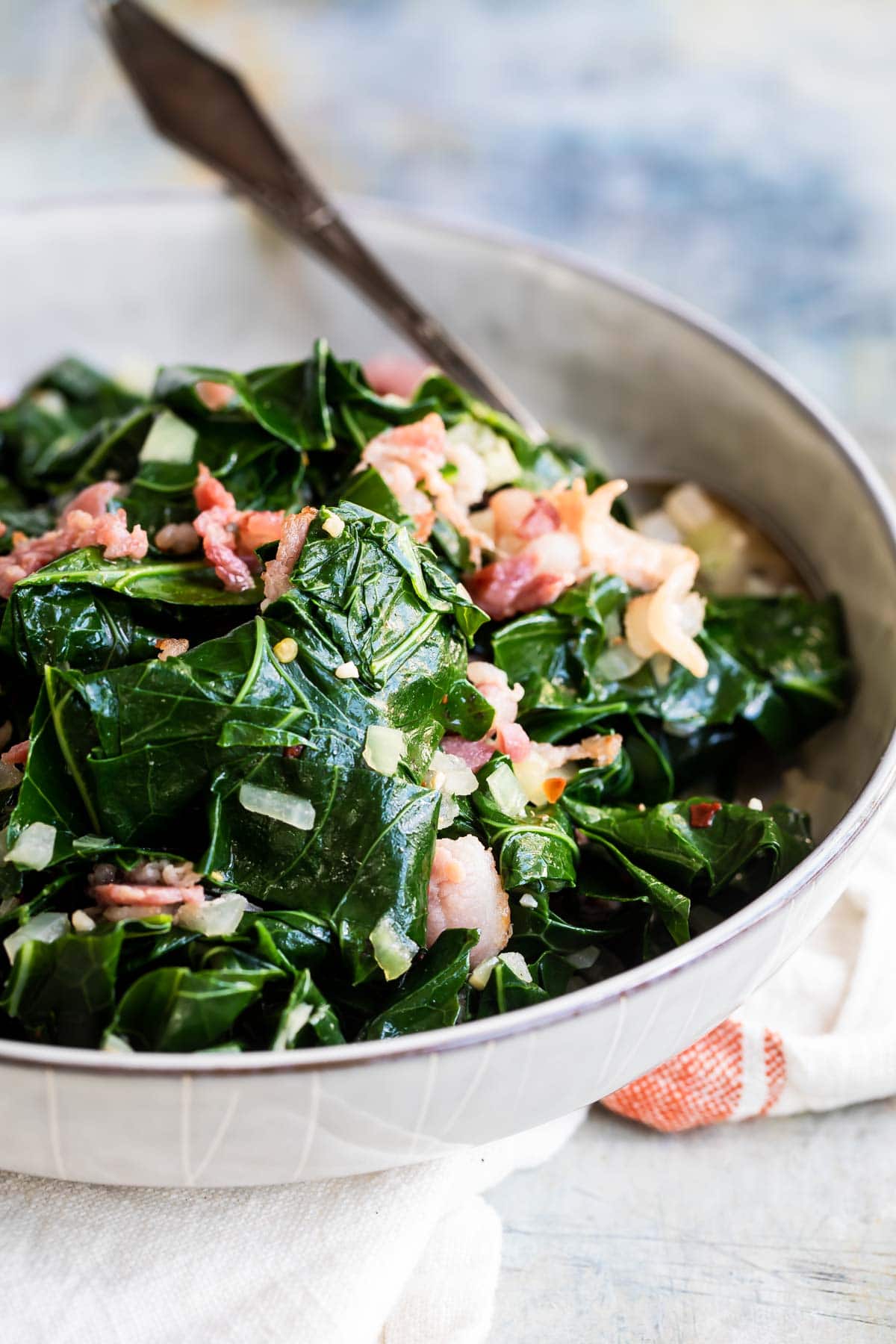 A skillet full of collard greens with bacon.