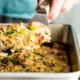 Someone scooping cornbread dressing out of a silver pan.