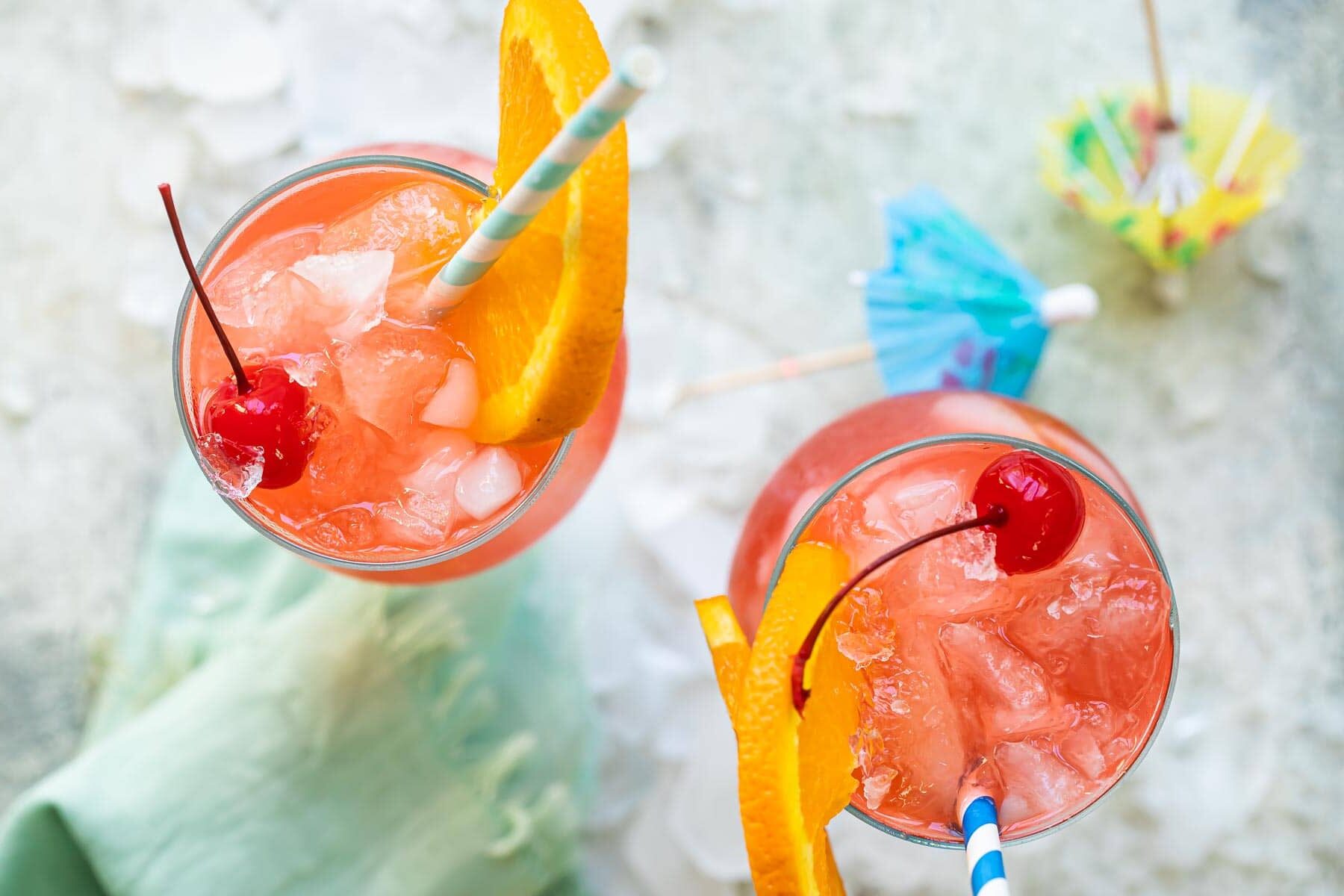 Two hurricane cocktails in hurricane glasses.