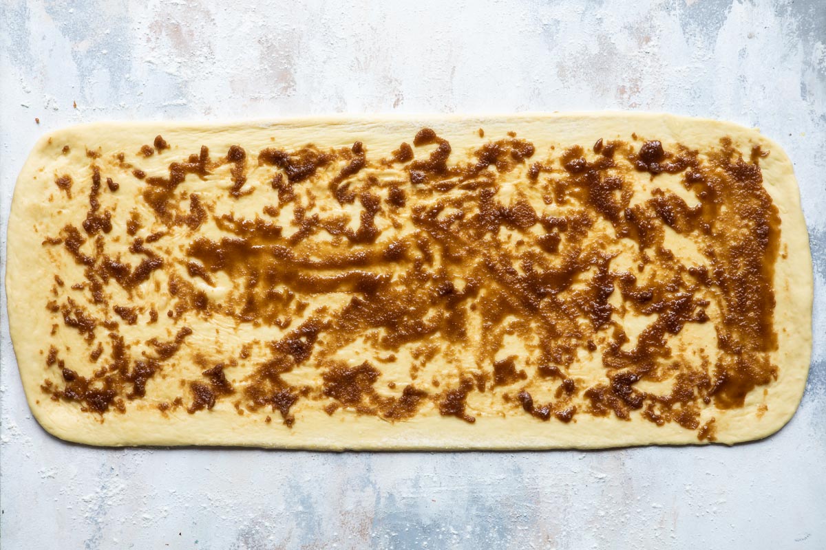 King cake dough rolled out into a long rectangle with filling spread out on it.