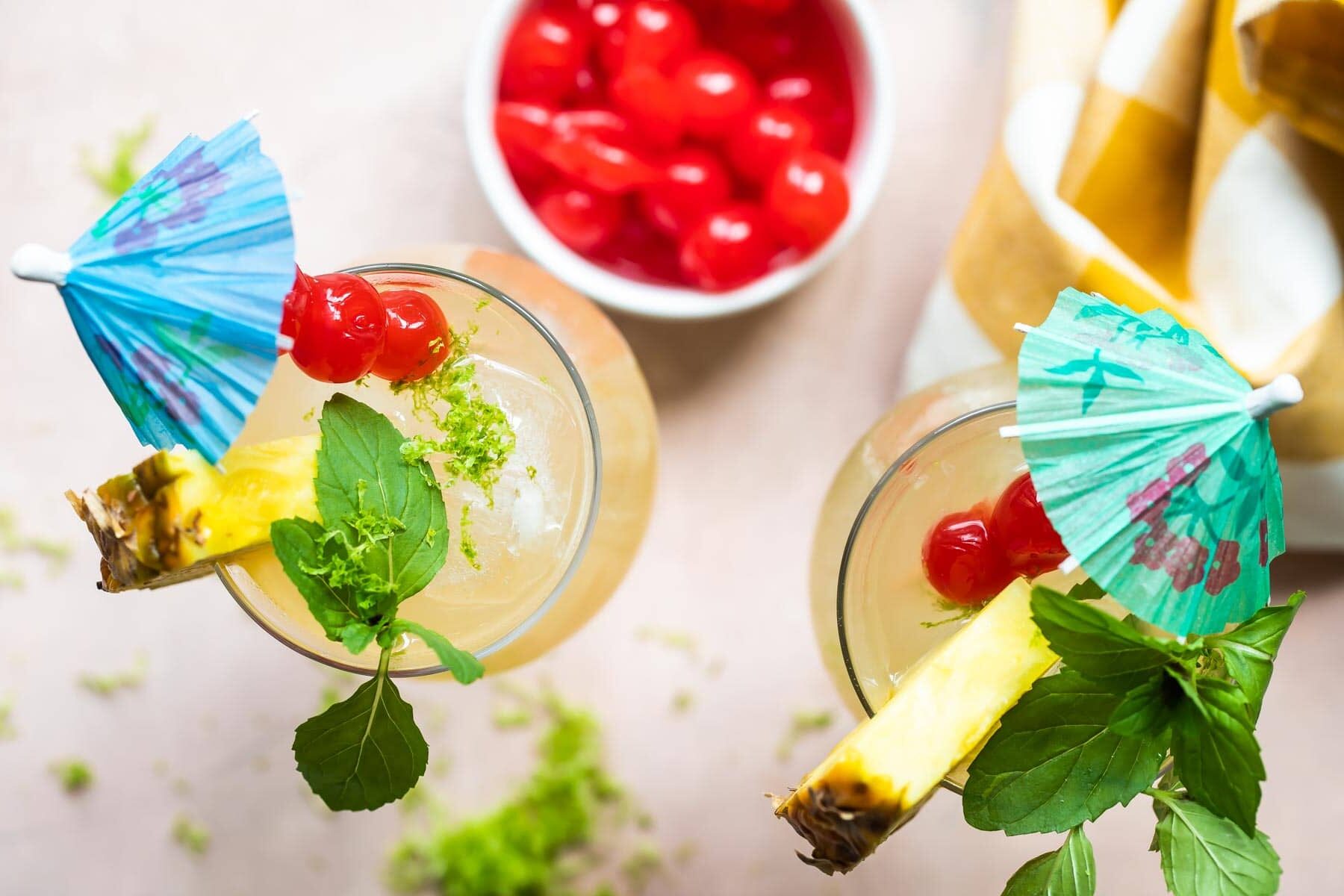Two Mai Tai cocktails in hurricane glasses.