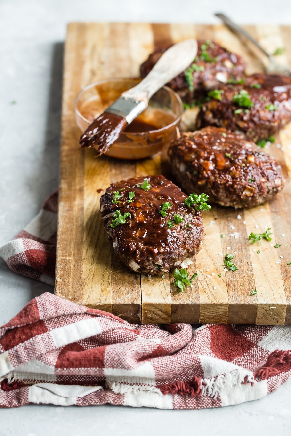 A cutting board with mini meatloaves on top.