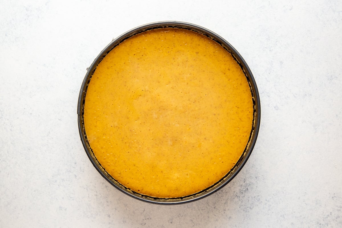 A baked pumpkin cheesecake cooling in a springform pan.