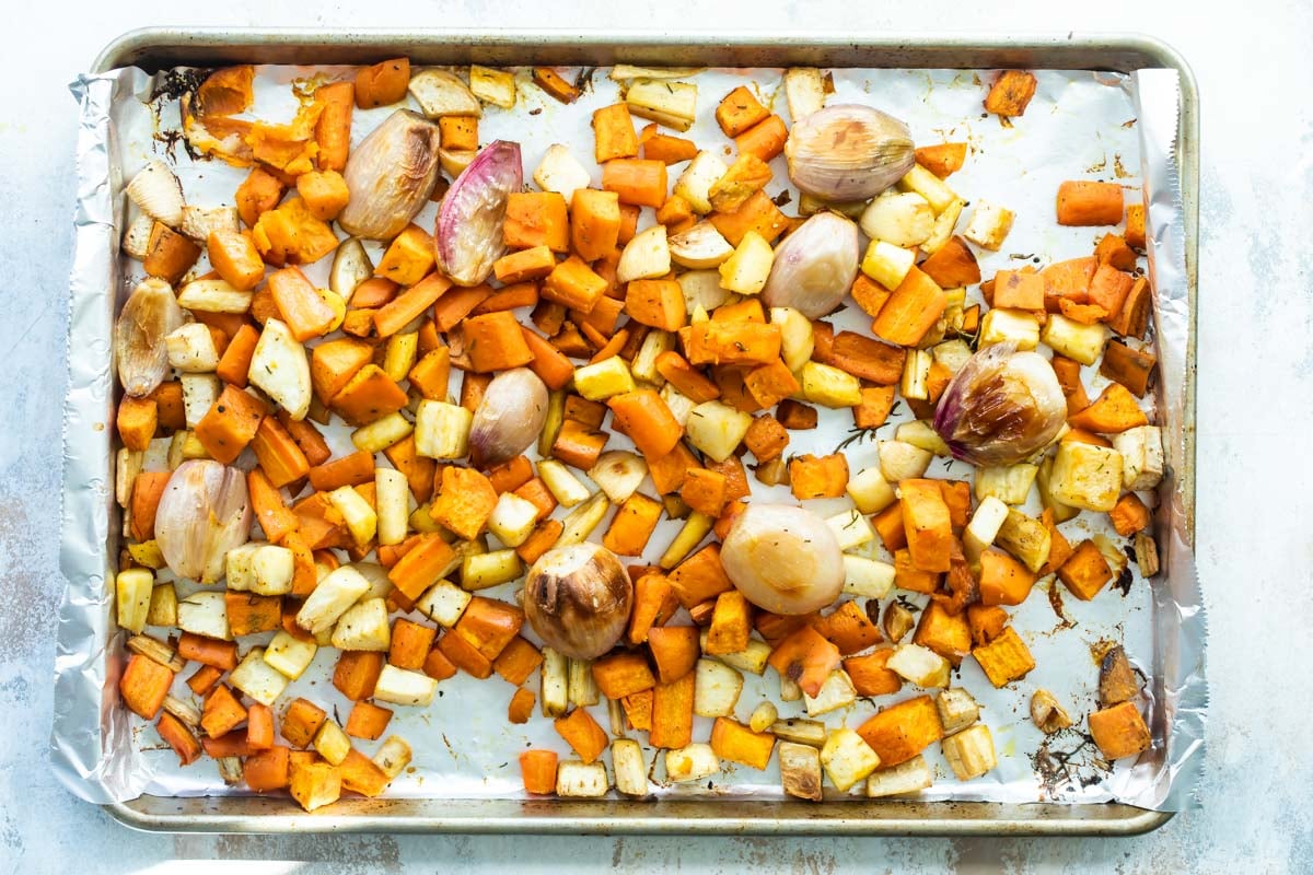 Roasted root vegetables on a parchment paper lined baking sheet.