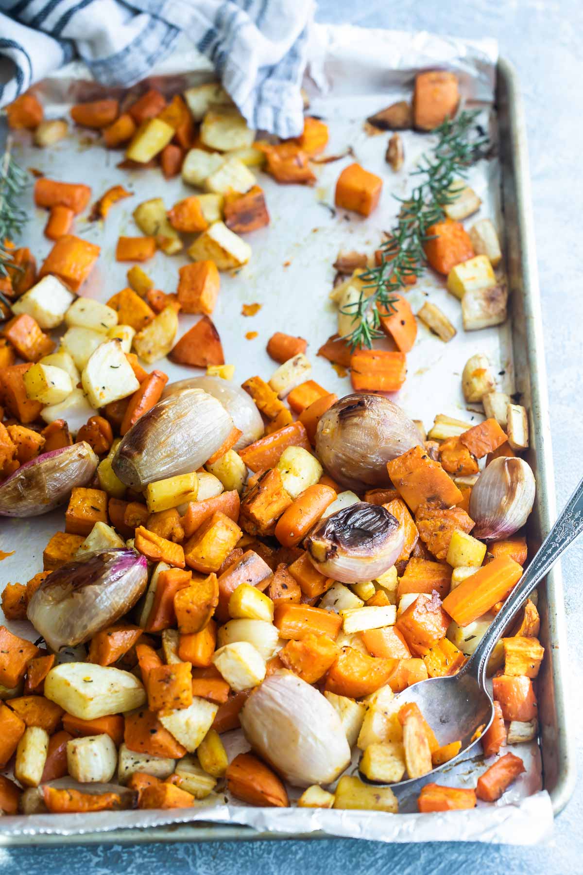 Roasted root vegetables on a parchment paper lined baking sheet.