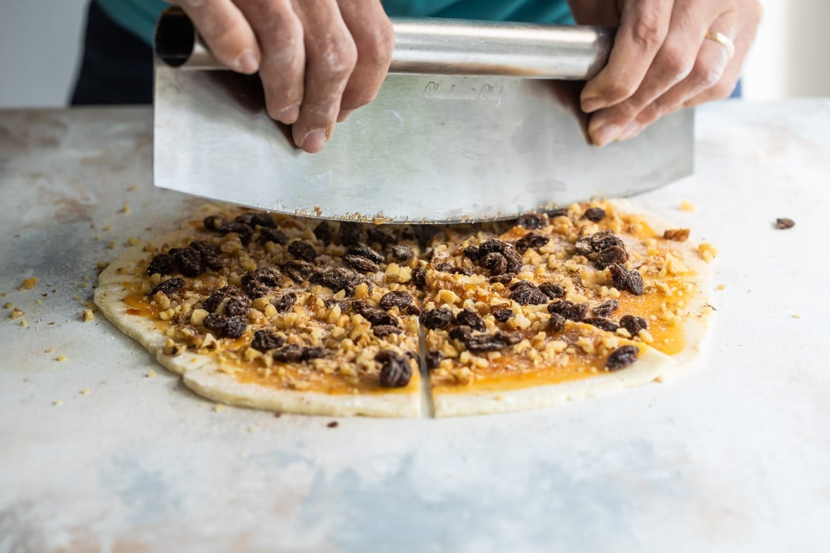 Someone slicing triangles of rugelach on a countertop.