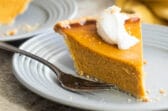 A slice of pumpkin pie on a gray plate.