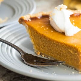 A slice of pumpkin pie on a gray plate.