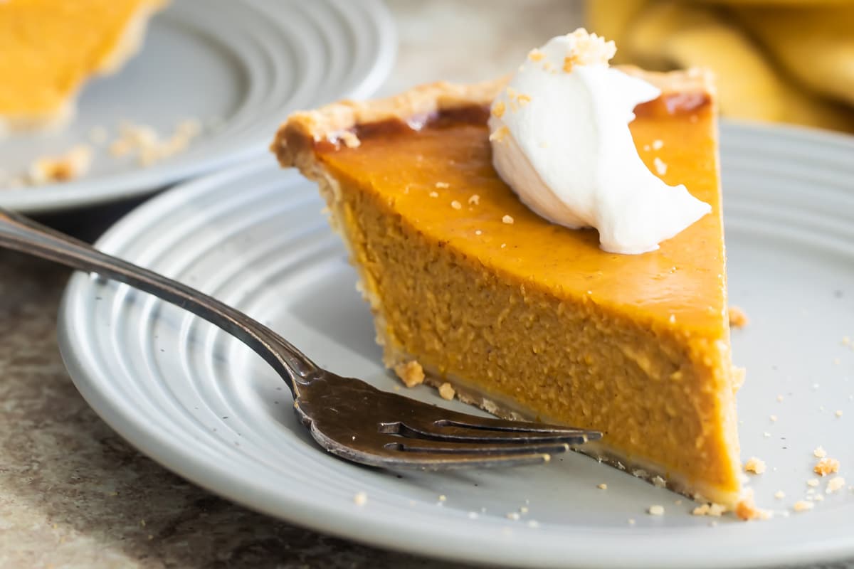A slice of pumpkin pie on a gray plate.