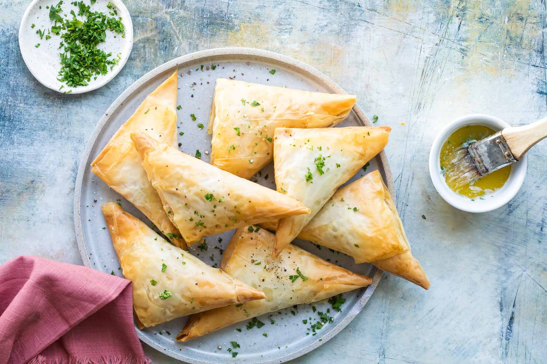 A pile of three cheese spanakopita triangles on a plate.