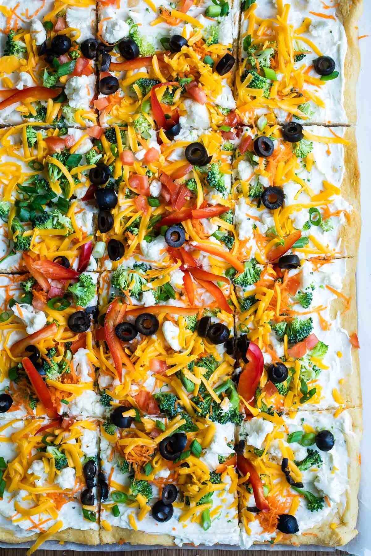 A veggie pizza on a wooden cutting board.
