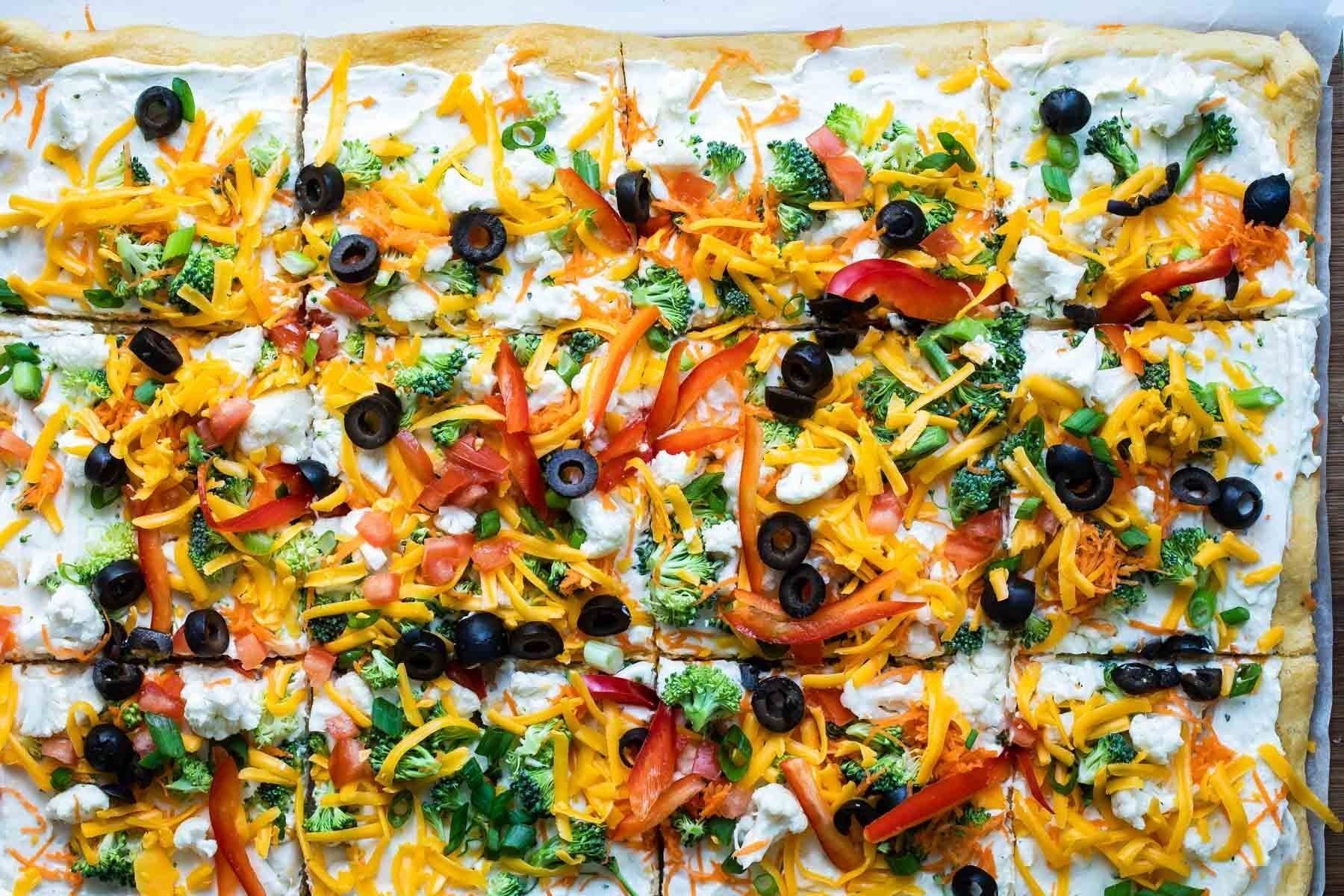 A veggie pizza on a wooden cutting board.