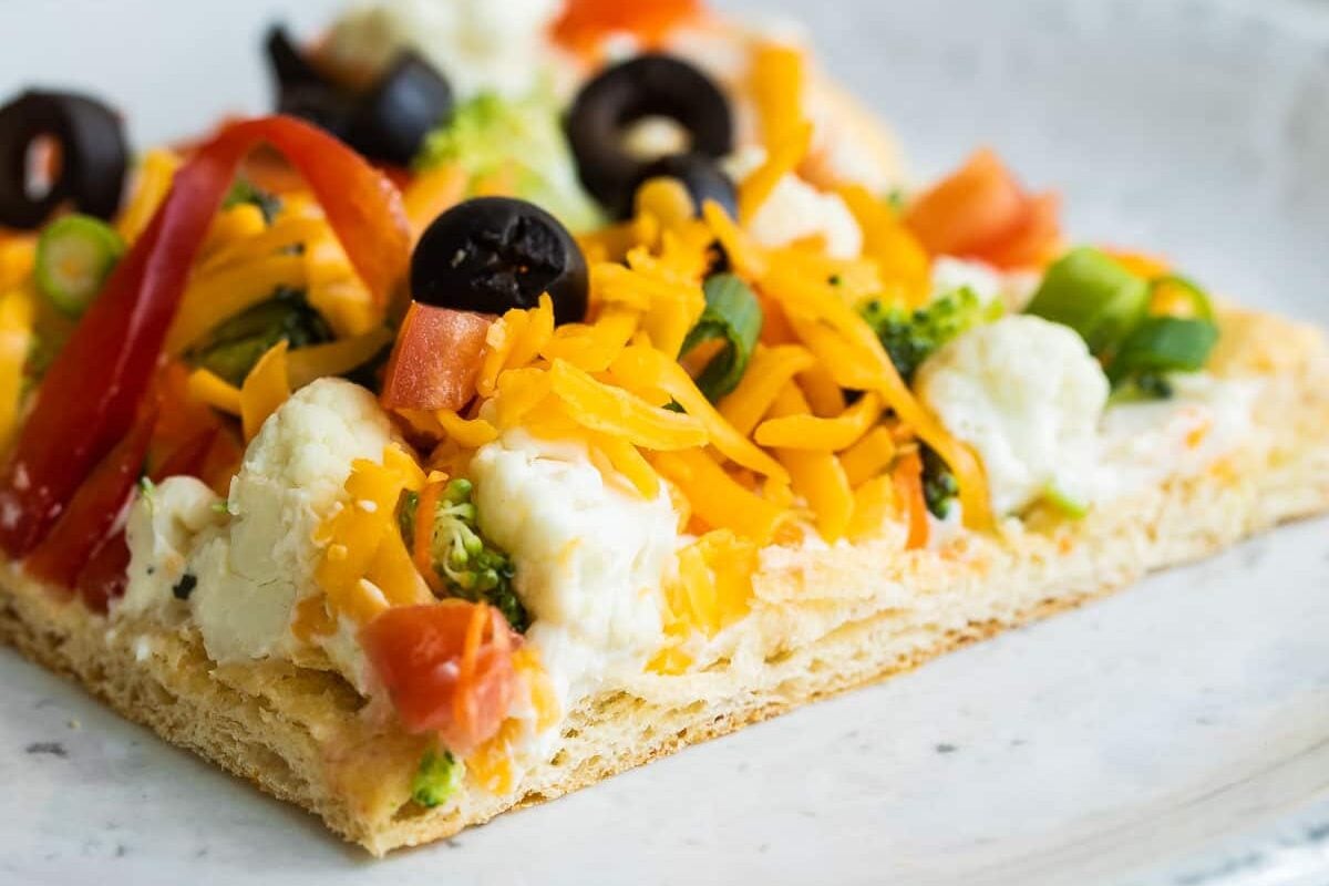 A square of veggie pizza on a gray plate.