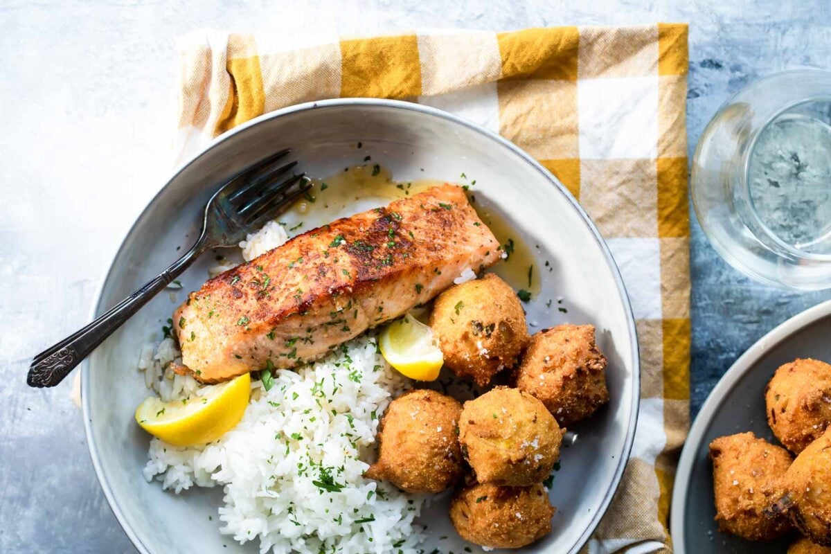 A plate with blackened salmon, hush puppies and rice.