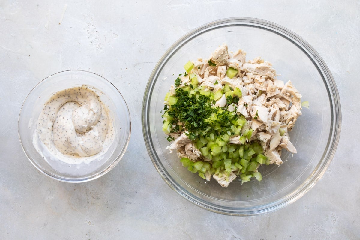 Chicken salad sauce next to a bowl of chicken salad ingredients.