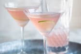 Two cosmopolitan cocktails on a galvanized metal serving tray.
