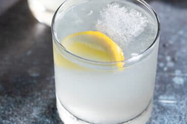 A gin fizz cocktail in glass with a lemon.
