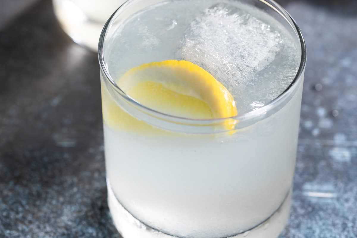 A gin fizz cocktail in glass with a lemon.