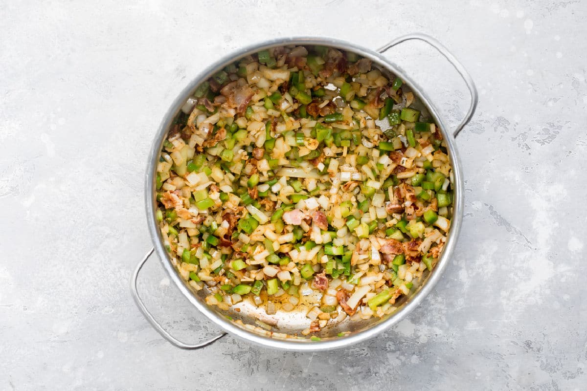 A skillet with bacon, onions, and peppers.