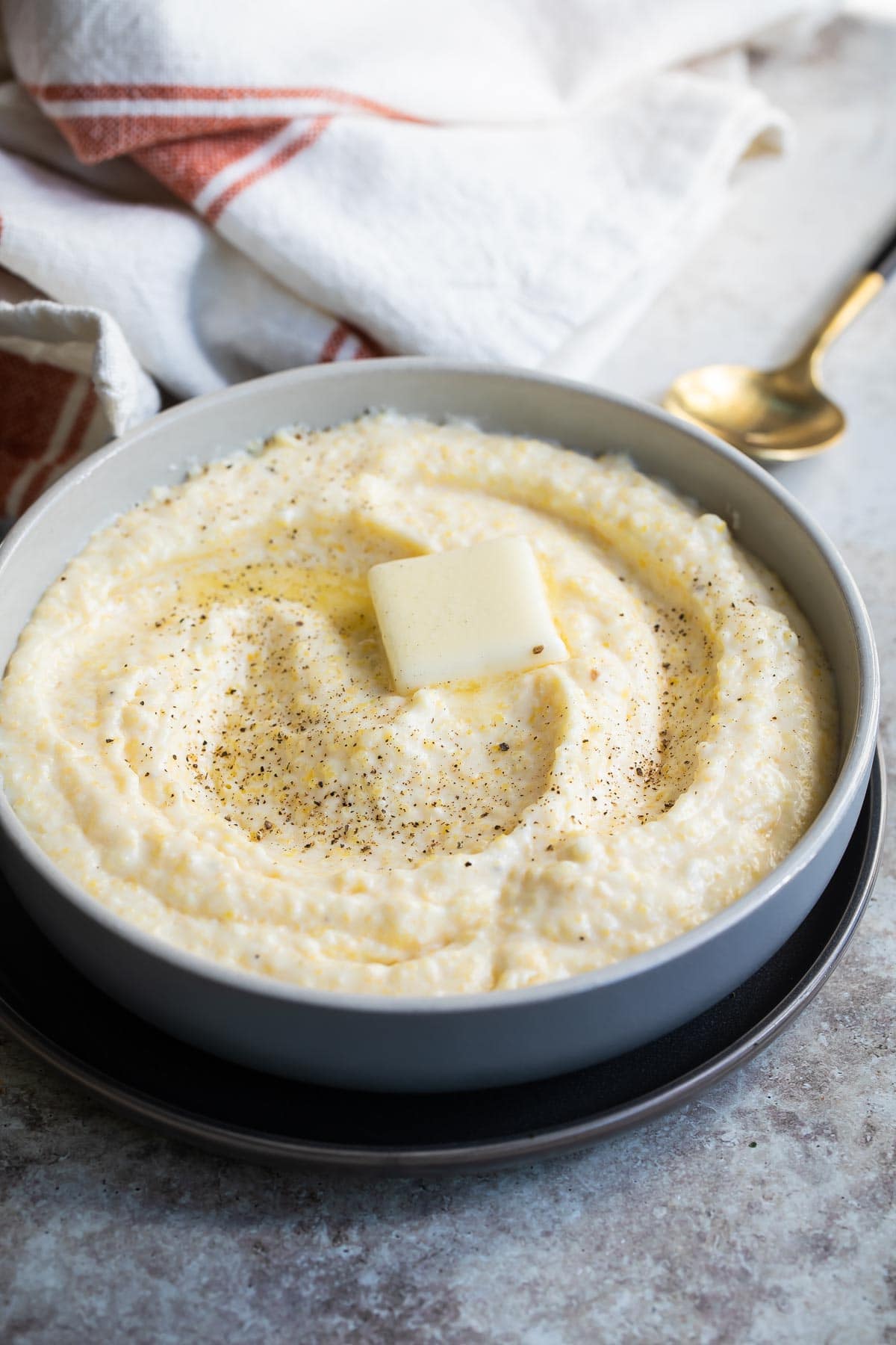 A bowl of grits with a pat of butter in the middle.
