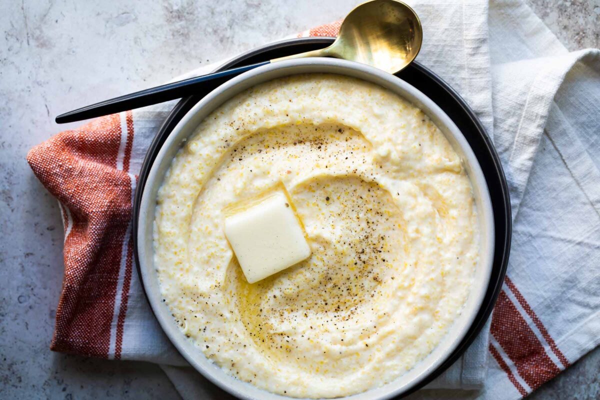 A bowl of grits with a pat of butter in the middle.